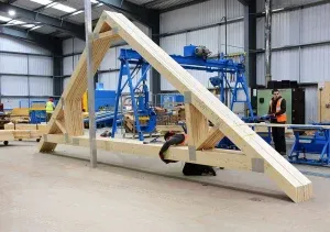 Worker packaging Roof Trusses in a warehouse with machinery and materials
