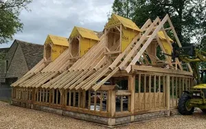 Building under construction with timber forming its structure with three dormers in the roof