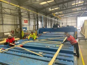 Three workers working across work benches and machinery