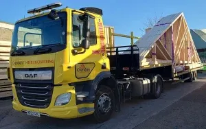 Yellow lorry holding roof trusses