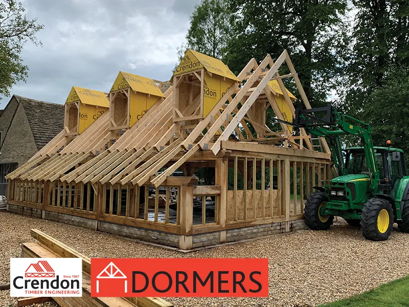 House under construction with three Dormers and a green tractor to its side