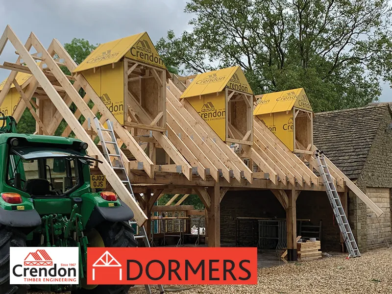 Building under construction with Dormers and a green tractor to its side