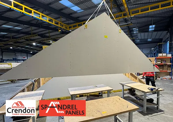 Spandrel panel lifted into the air with a worker assisting